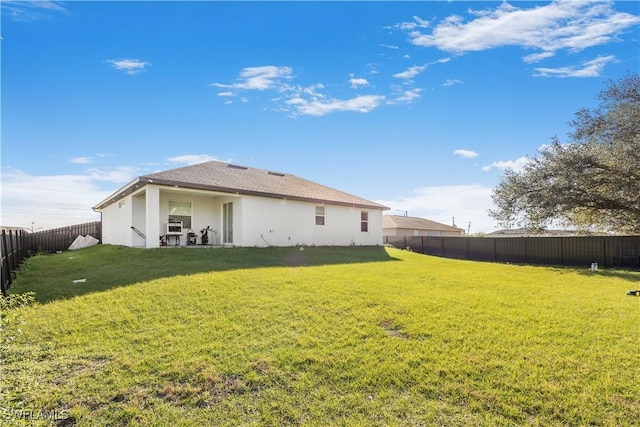 back of house featuring a yard, a fenced backyard, and stucco siding