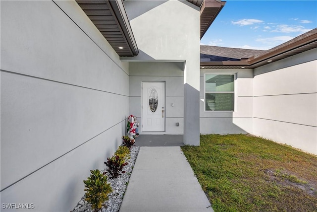 property entrance with a yard and stucco siding