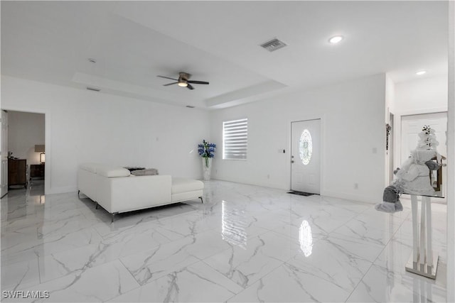 living area with a raised ceiling, recessed lighting, visible vents, and marble finish floor