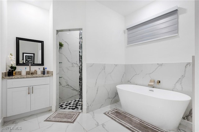 bathroom featuring a wainscoted wall, marble finish floor, a marble finish shower, a soaking tub, and vanity