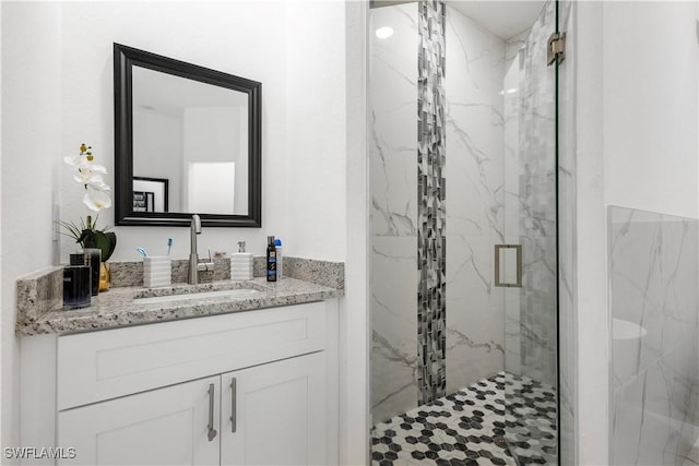 full bathroom featuring a marble finish shower and vanity