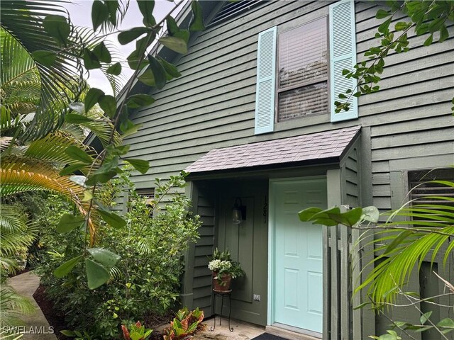 view of exterior entry with a shingled roof