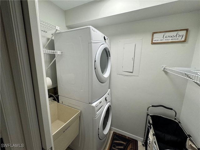 1281 Solana Rd, Naples, FL 34103 - laundry area featuring baseboards, electric panel, laundry area, stacked washing maching and dryer, and a sink