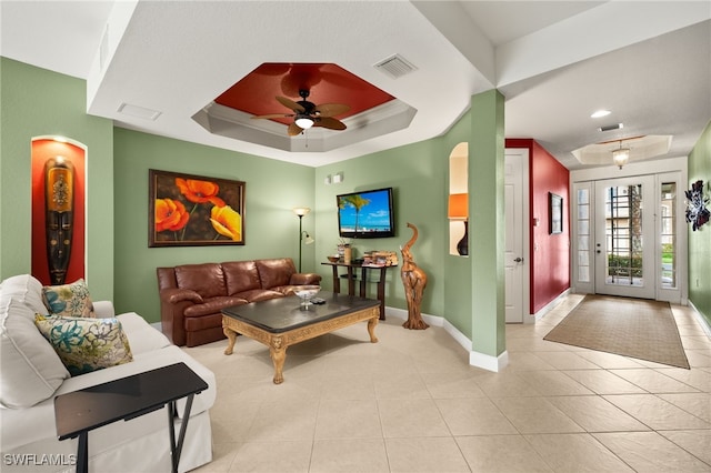 living area with visible vents, a tray ceiling, light tile patterned flooring, baseboards, and ceiling fan