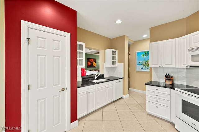 kitchen featuring dark countertops, white cabinets, white appliances, and a sink