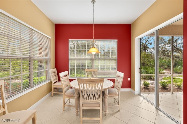 dining area featuring light tile patterned flooring, an accent wall, and baseboards