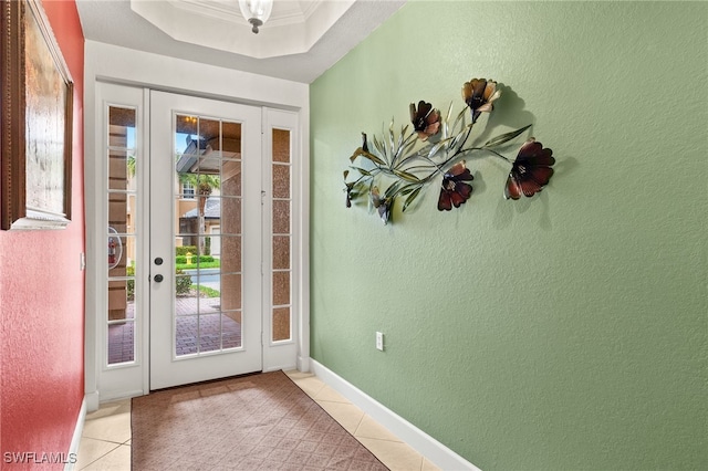 doorway to outside with a raised ceiling, light tile patterned flooring, ornamental molding, and a textured wall