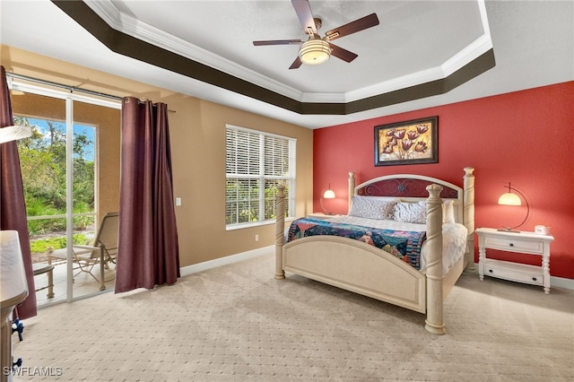 carpeted bedroom featuring access to exterior, a tray ceiling, and ornamental molding