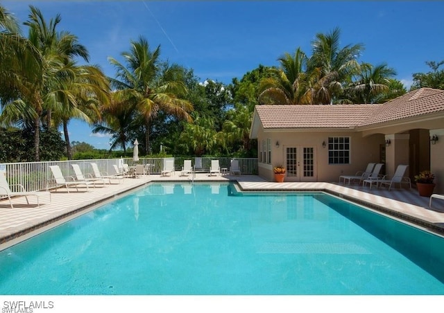 pool with a patio area, french doors, and fence