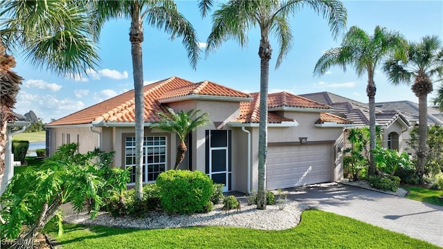 mediterranean / spanish-style home featuring stucco siding, driveway, a tile roof, and a garage