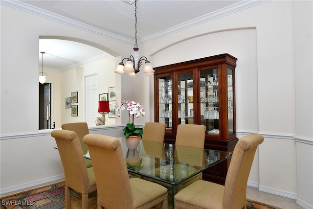 dining room featuring baseboards, arched walkways, an inviting chandelier, and crown molding