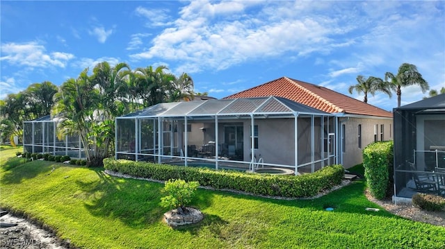 rear view of house featuring a lanai, a tiled roof, a lawn, and stucco siding