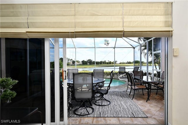 wooden terrace featuring outdoor dining area, a water view, and a lanai