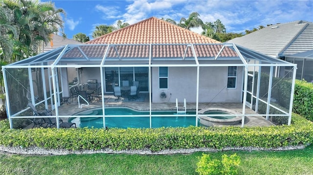 back of house featuring stucco siding, a tile roof, glass enclosure, and a patio area