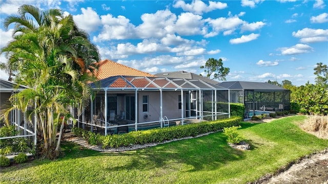 rear view of property featuring glass enclosure, a yard, stucco siding, and a tile roof