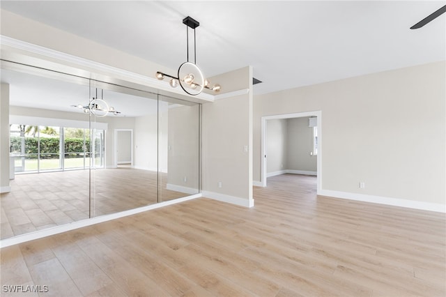 interior space featuring baseboards, ceiling fan with notable chandelier, and light wood-type flooring