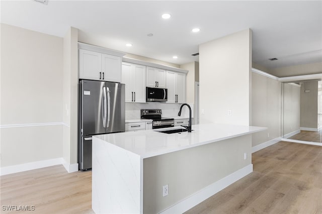 kitchen with light countertops, stainless steel appliances, a sink, and light wood-style flooring