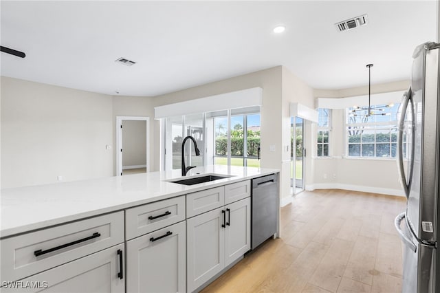 kitchen with visible vents, pendant lighting, a sink, a notable chandelier, and stainless steel appliances