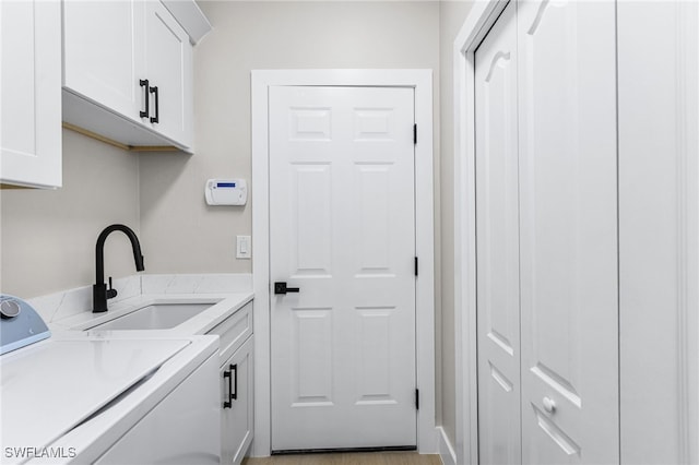 washroom with a sink, cabinet space, and washer and dryer