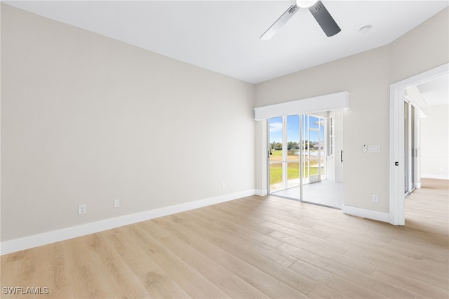 empty room featuring a ceiling fan, baseboards, and light wood-type flooring
