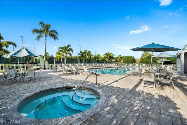 pool featuring outdoor dining area, a patio area, a community hot tub, and fence