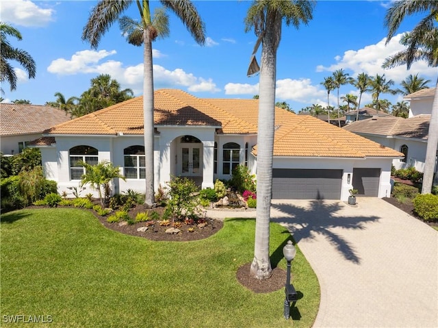 mediterranean / spanish home featuring stucco siding, a tile roof, french doors, a front yard, and an attached garage