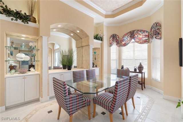 dining space featuring baseboards, a high ceiling, arched walkways, crown molding, and a raised ceiling