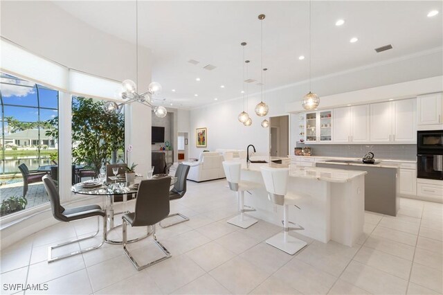 kitchen with backsplash, a center island with sink, white cabinetry, and black appliances