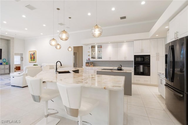 kitchen featuring a spacious island, open floor plan, black appliances, and a sink