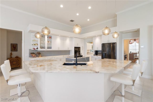 kitchen with ornamental molding, a large island, white cabinets, fridge with ice dispenser, and backsplash