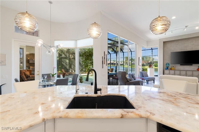 kitchen with decorative light fixtures, open floor plan, light stone countertops, and a sink