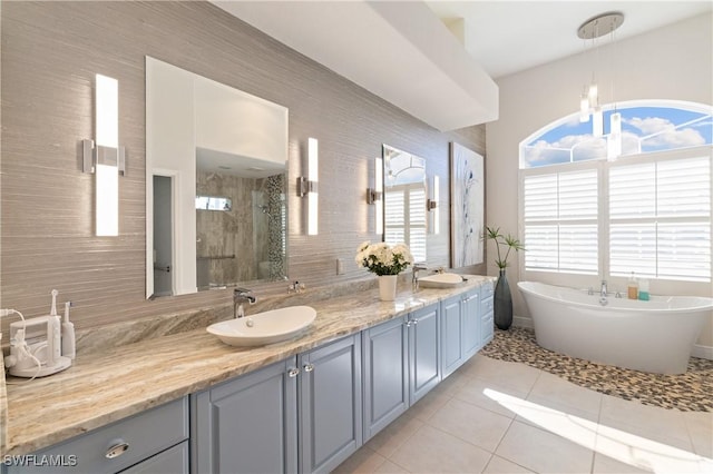 full bath featuring a sink, a stall shower, double vanity, and tile patterned floors