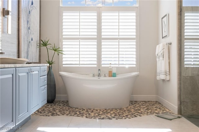 full bathroom with vanity, a soaking tub, baseboards, and tile patterned flooring