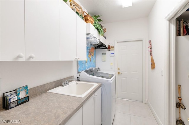 washroom featuring cabinet space, light tile patterned floors, washing machine and dryer, and a sink