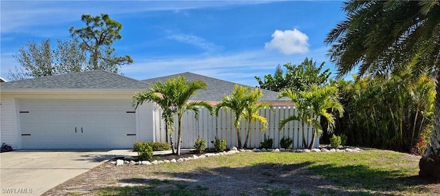 view of front of property featuring concrete driveway, an attached garage, fence, and a shingled roof