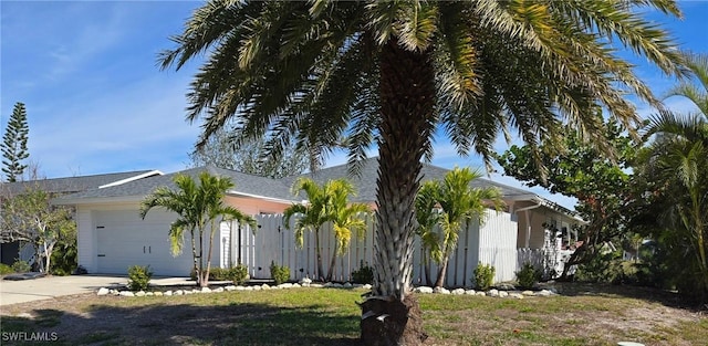 view of front of house featuring a garage, driveway, and fence