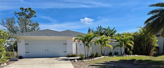 single story home featuring roof with shingles, concrete driveway, and fence