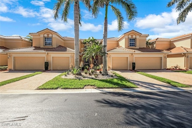 view of front of property featuring stucco siding, a tiled roof, and decorative driveway