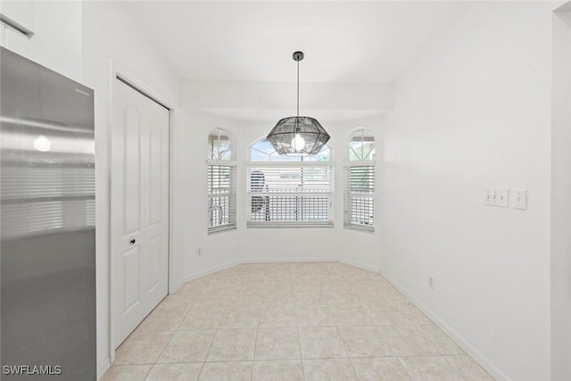 unfurnished dining area featuring light tile patterned flooring, baseboards, and a wealth of natural light