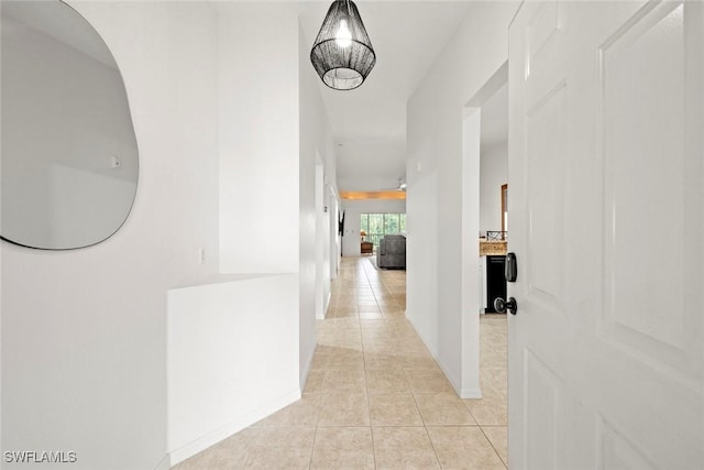 hallway with light tile patterned floors and baseboards