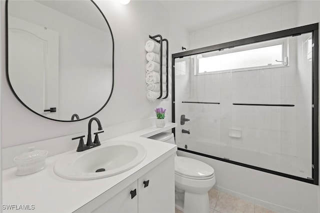 full bath with tile patterned floors, toilet, vanity, and shower / bath combination with glass door