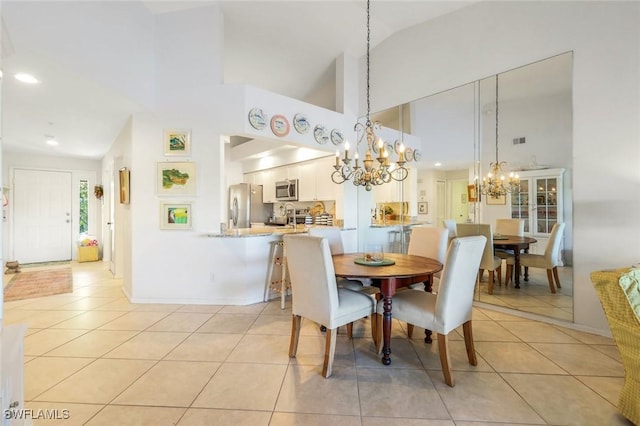 dining space with a notable chandelier, light tile patterned flooring, baseboards, and high vaulted ceiling