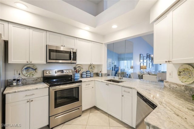 kitchen featuring light stone counters, white cabinetry, stainless steel appliances, and a sink