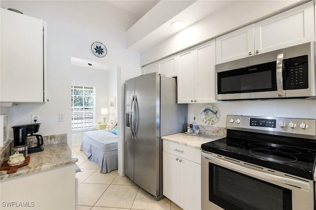 kitchen featuring white cabinetry, light tile patterned floors, light stone countertops, and stainless steel appliances