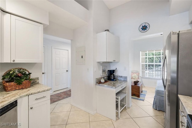 kitchen featuring electric panel, stainless steel appliances, light tile patterned flooring, and white cabinetry