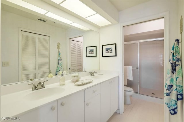 full bath with visible vents, toilet, a sink, a shower stall, and double vanity