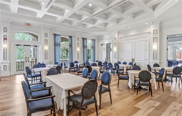 dining area featuring beam ceiling, a decorative wall, light wood finished floors, and a high ceiling