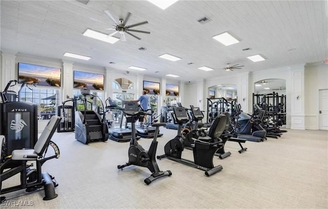 gym with visible vents, ceiling fan, carpet flooring, a decorative wall, and ornate columns