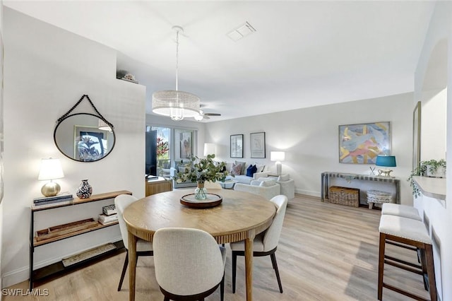 dining space with a notable chandelier, light wood-style floors, visible vents, and baseboards