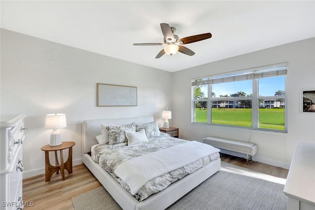 bedroom featuring light wood-style flooring, a ceiling fan, and baseboards